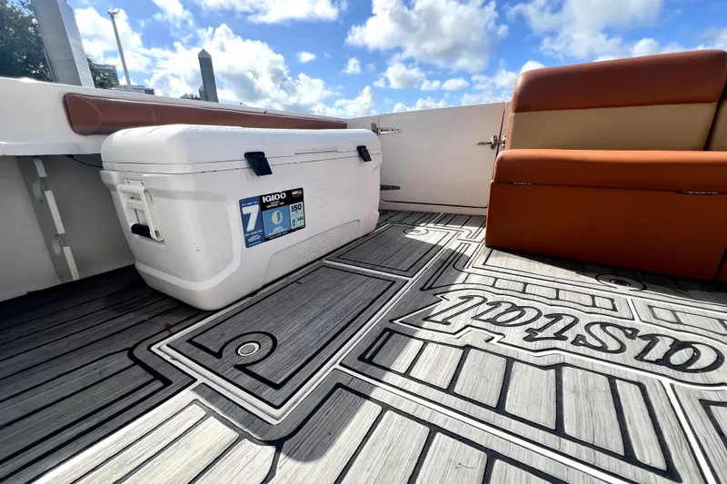Slide: The Image of 1996 Wellcraft 330 Coastal boat interior with cushioned seating and patterned flooring under a cloudy sky. - 26