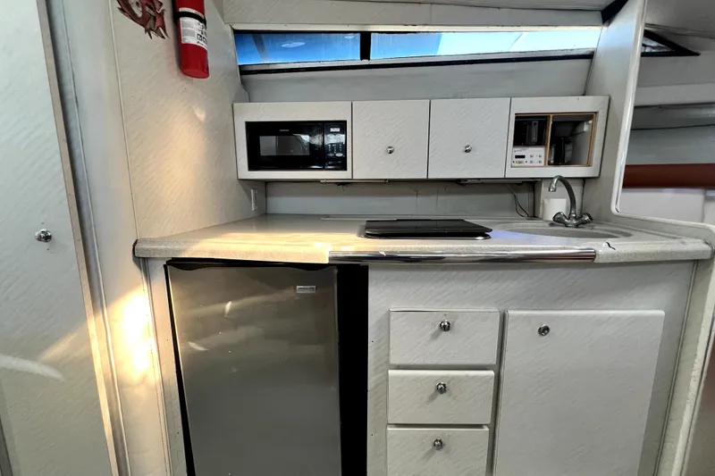 Slide: The Image of 1996 Wellcraft 330 Coastal cabin interior with nautical-themed pillows and porthole windows. - 60