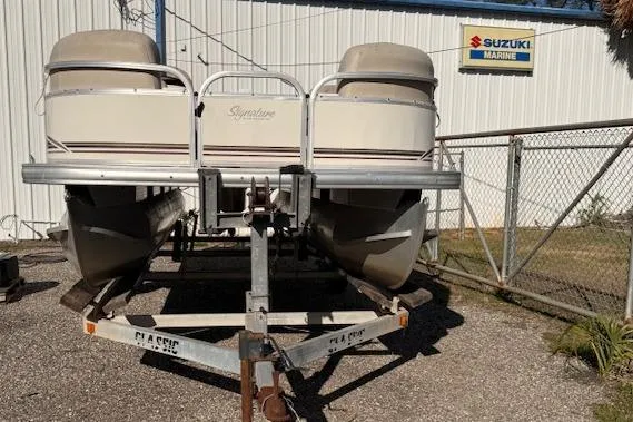 Slide: The Image of 2011 Sun Tracker Party Barge 21 Signature Series on trailer near Suzuki Marine sign. - 3