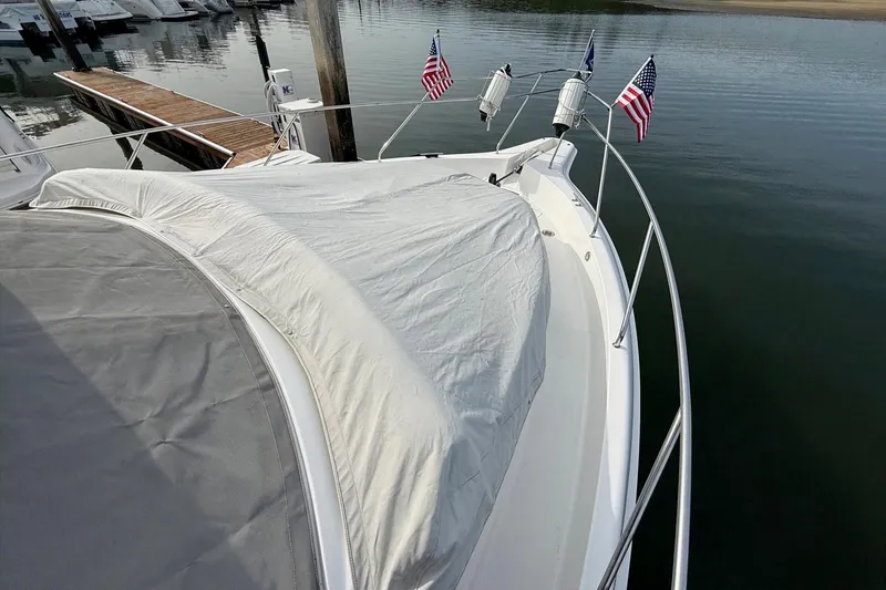 Slide: The Image of 1999 Silverton 392 Motor Yacht docked, covered deck, American flags, calm water. - 14