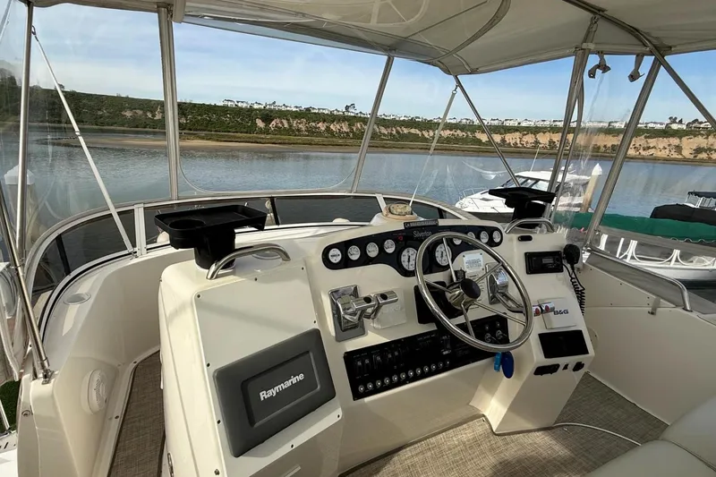 Slide: The Image of 1999 Silverton 392 Motor Yacht helm with Raymarine equipment, docked by a scenic river. - 21
