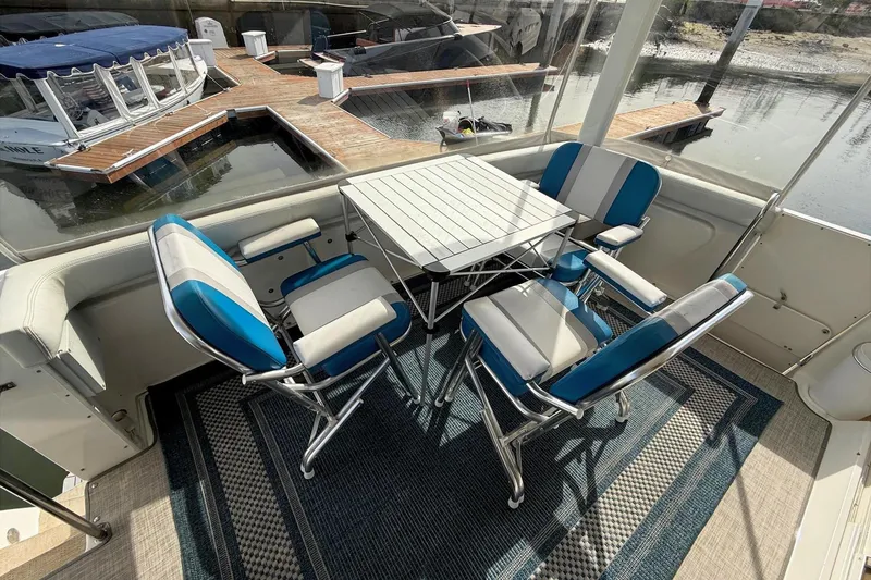 Slide: The Image of 1999 Silverton 392 Motor Yacht interior with blue and white seating, table, and marina view. - 27