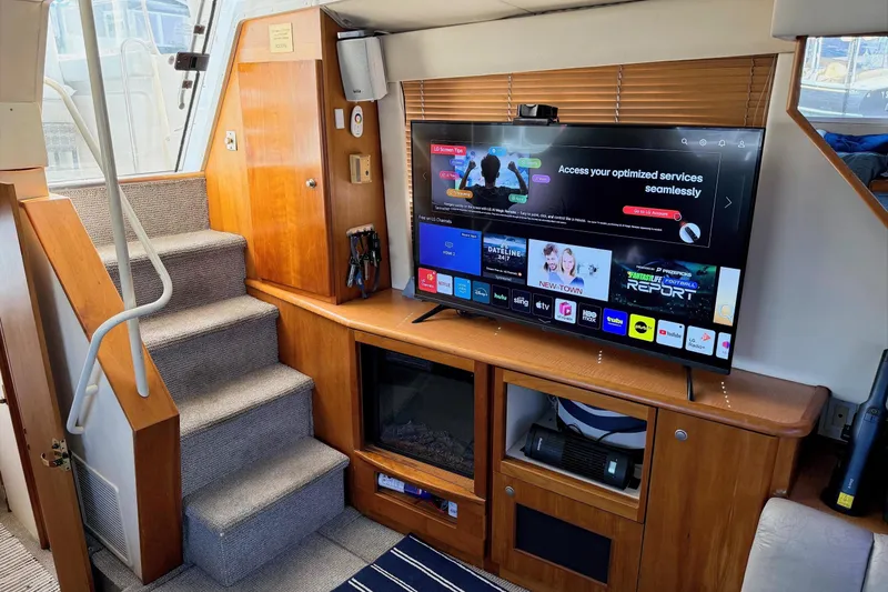 Slide: The Image of 1999 Silverton 392 Motor Yacht interior with TV, wooden cabinetry, and carpeted stairs. - 32