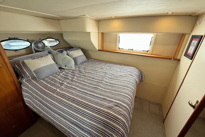 Slide: The Image of Cozy bedroom in 1999 Silverton 392 Motor Yacht with striped bedding and porthole windows. - 42