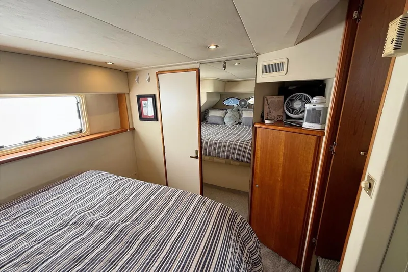 Slide: The Image of 1999 Silverton 392 Motor Yacht interior bedroom with striped bedding and wooden cabinetry. - 45