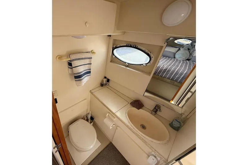 Slide: The Image of Bathroom interior of 1999 Silverton 392 Motor Yacht with sink, toilet, and porthole window. - 47