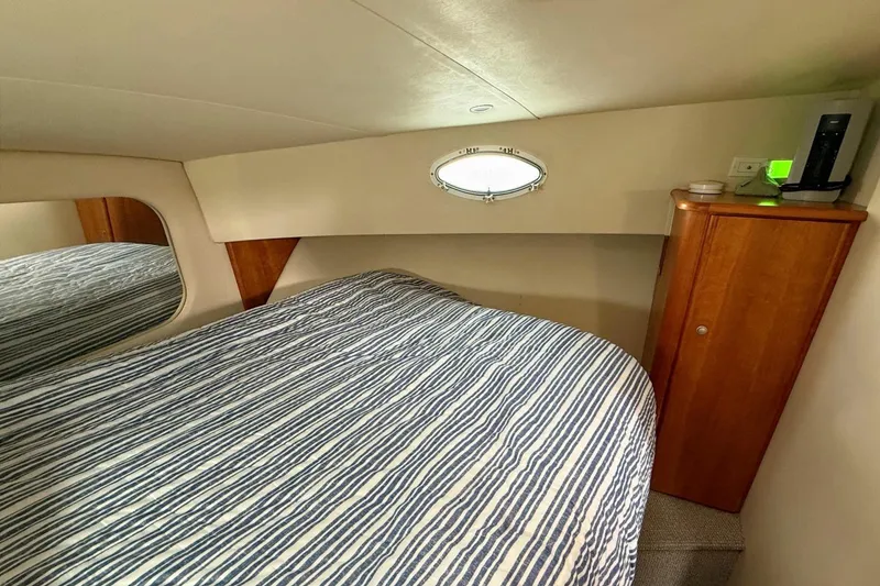 Slide: The Image of 1999 Silverton 392 Motor Yacht bedroom with striped bedding and wooden cabinetry. - 50