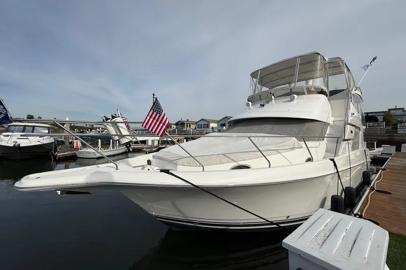 Slide: The Image of 1999 Silverton 392 Motor Yacht docked with American flag, clear sky background. - 6