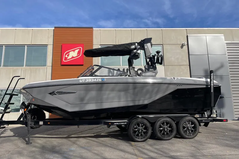 The Image of 2024 Nautique Super Air Nautique G23 boat on trailer, parked outside dealership. - 1