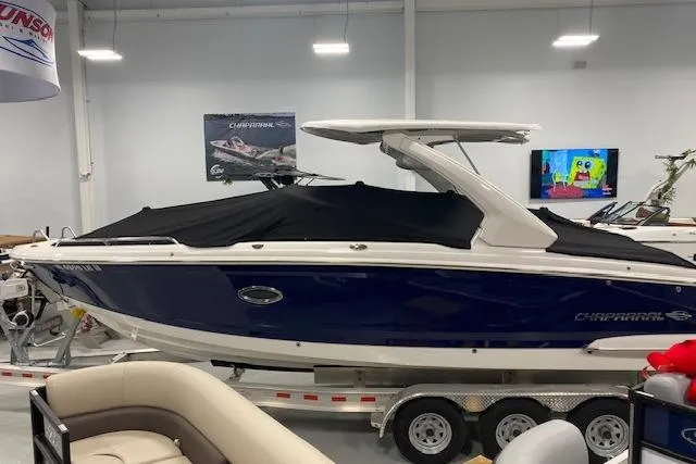 Slide: The Image of 2023 Chaparral 307 SSX boat in showroom, blue hull, black cover, on trailer. - 14