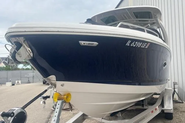 Slide: The Image of 2023 Chaparral 307 SSX boat on trailer, blue and white exterior, parked near a building. - 50