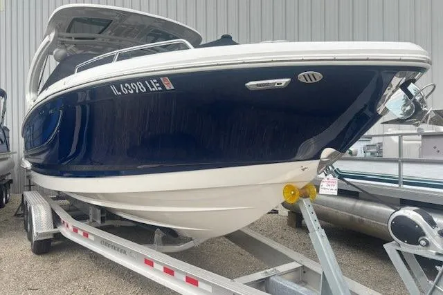Slide: The Image of 2023 Chaparral 307 SSX boat on trailer, blue and white hull, parked outdoors. - 52