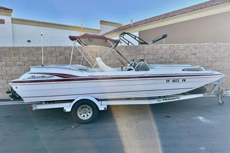 The Image of 2000 Godfrey Hurricane 2100 Sundeck boat on trailer, parked outdoors. - 0