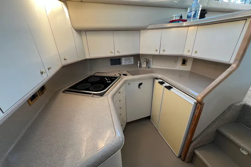 Slide: The Image of 1997 Sea Ray 370 Aft Cabin kitchen with stove, sink, and cabinets. - 38