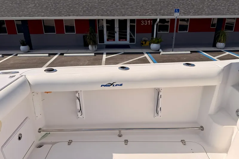 Slide: The Image of 2007 Pro-Line 32 Express boat interior with rod holders and seating, parked near a building. - 23