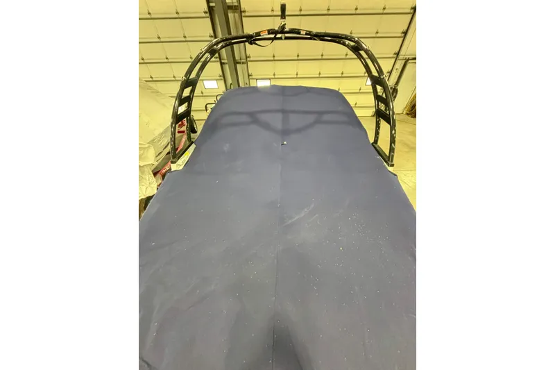 Slide: The Image of 2021 Chaparral 23 SSi boat covered in a blue tarp inside a garage. - 21
