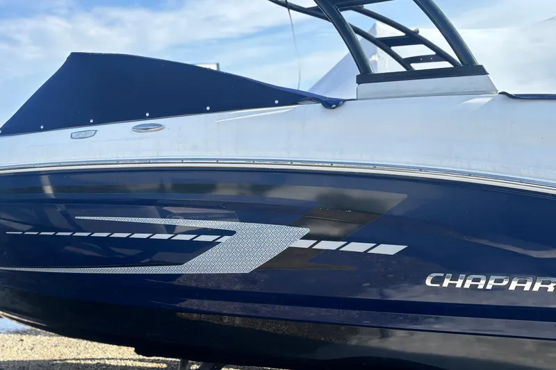 Slide: The Image of 2021 Chaparral 23 SSi boat with sleek blue and white design under a clear sky. - 6