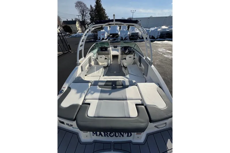 Slide: The Image of 2022 Chaparral 23 SSi OB boat interior with seating and helm, parked outdoors. - 15