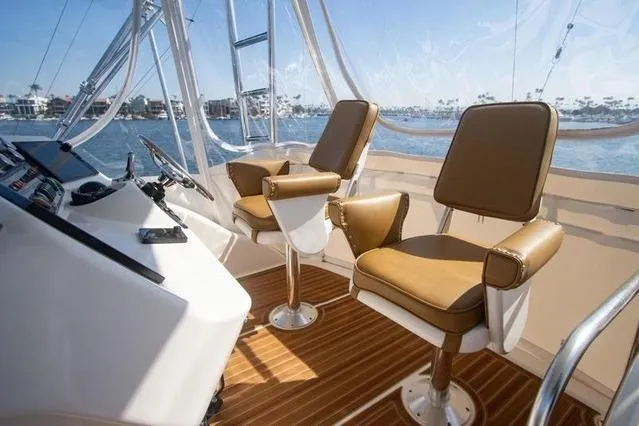 Slide: The Image of 2003 Riviera 4700 Sport Yacht helm with brown seats and ocean view. - 33