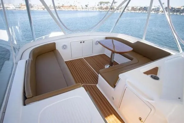 Slide: The Image of 2003 Riviera 4700 Sport Yacht interior with elegant seating and wooden table, overlooking serene waters. - 36