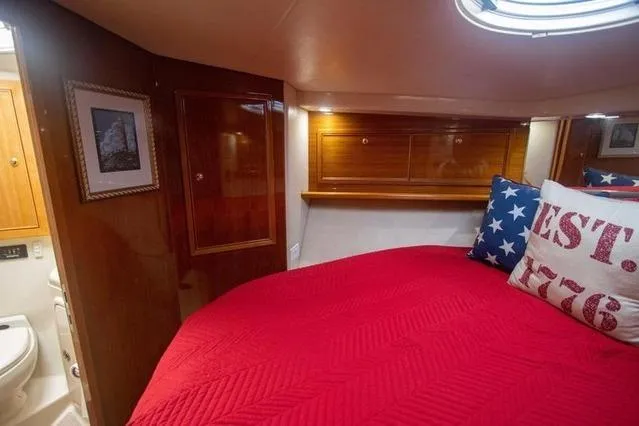 Slide: The Image of Cozy cabin interior of 2003 Riviera 4700 Sport Yacht with red bedding and nautical decor. - 49