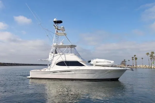 Slide: The Image of 2003 Riviera 4700 Sport Yacht on calm water, clear sky, coastal background. - 12