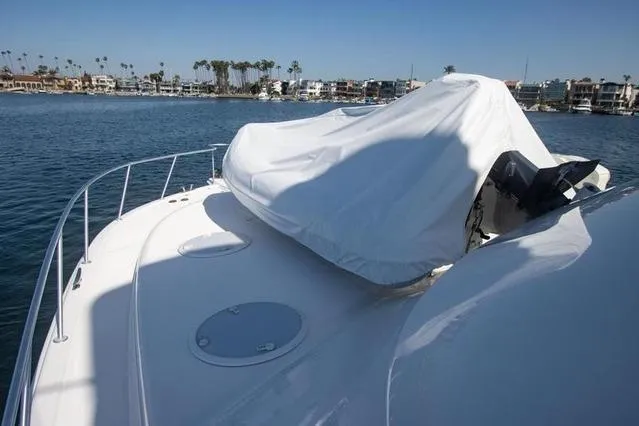 Slide: The Image of 2003 Riviera 4700 Sport Yacht on water, covered deck, coastal view in background. - 24