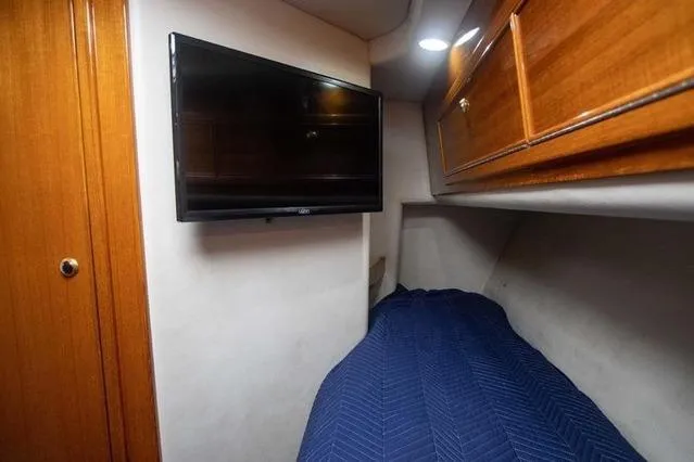 Slide: The Image of Interior cabin of 2003 Riviera 4700 Sport Yacht with TV and blue bedding. - 40