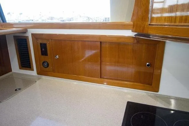 Slide: The Image of 2003 Riviera 4700 Sport Yacht interior with polished wood cabinetry and modern countertop. - 53