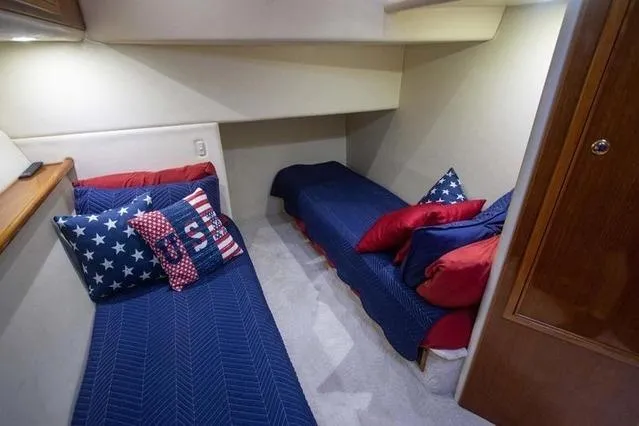 Slide: The Image of 2003 Riviera 4700 Sport Yacht cabin with twin beds, patriotic-themed bedding. - 69