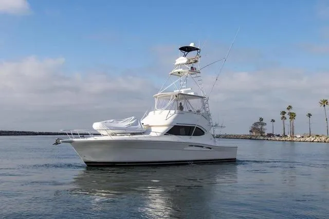Slide: The Image of 2003 Riviera 4700 Sport Yacht cruising on calm waters under a clear sky. - 8