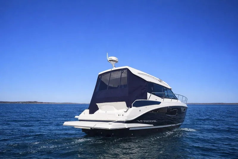 Slide: The Image of 2019 Regal 42 Grande Coupe yacht cruising on open water under clear blue sky. - 2