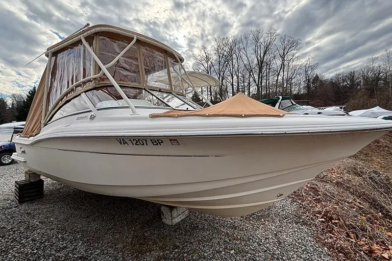 Slide: The Image of 2007 Scout 222 Dorado boat on gravel, under cloudy sky, with protective cover. - 2