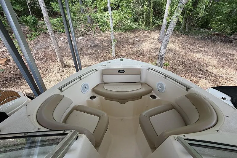 Slide: The Image of 2007 Scout 222 Dorado boat interior with beige seating, surrounded by lush greenery. - 23