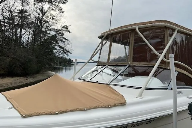 Slide: The Image of 2007 Scout 222 Dorado boat with tan canopy, docked near a wooded shoreline. - 5