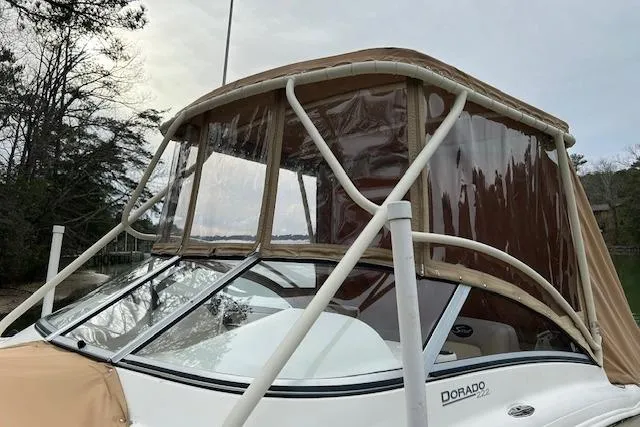 Slide: The Image of 2007 Scout 222 Dorado boat with brown canopy and clear windows, docked near trees. - 6