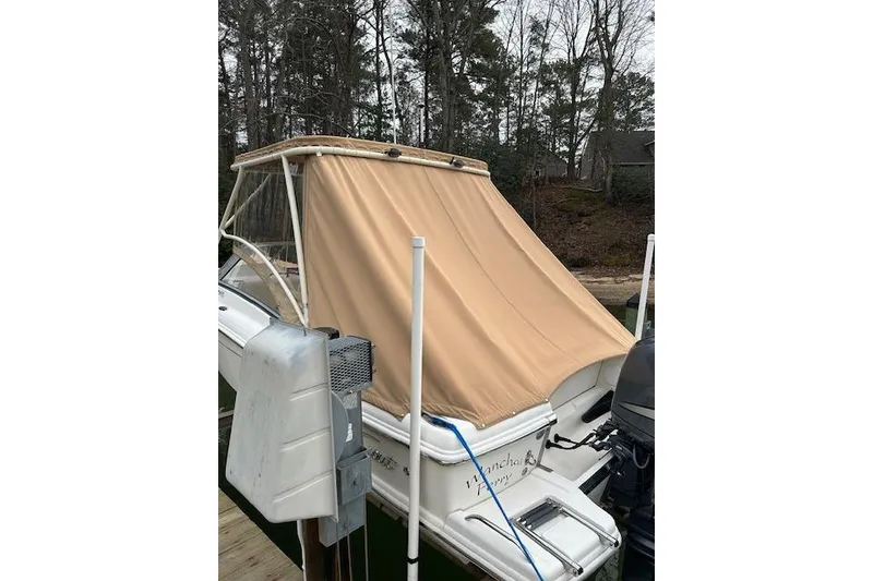 Slide: The Image of 2007 Scout 222 Dorado boat with tan cover docked near wooded area. - 7