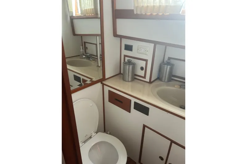 Slide: The Image of 1996 Grand Banks 36 Motoryacht kitchen with sink, microwave, and stove, featuring wooden cabinetry. - 21