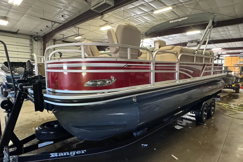 Slide: The Image of 2020 Ranger Reata 220F pontoon boat in a garage, featuring red and gray design. - 1