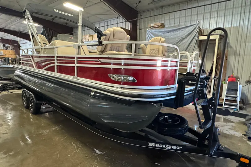 Slide: The Image of 2020 Ranger Reata 220F pontoon boat in a garage, featuring red and beige design. - 2