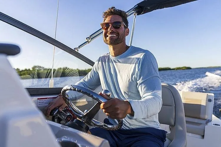 Slide: The Image of Man steering 2024 Boston Whaler 210 Vantage boat on sunny day. - 15