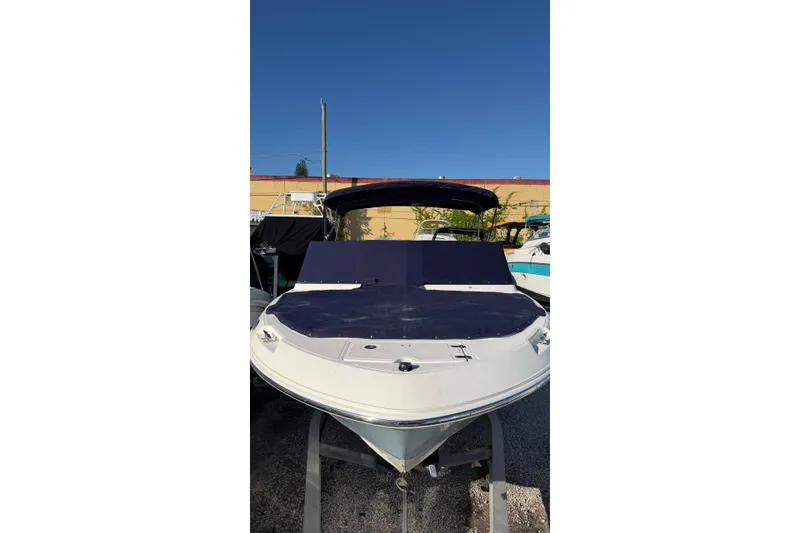 Slide: The Image of 2024 Boston Whaler 210 Vantage boat with blue cover, docked outdoors. - 2