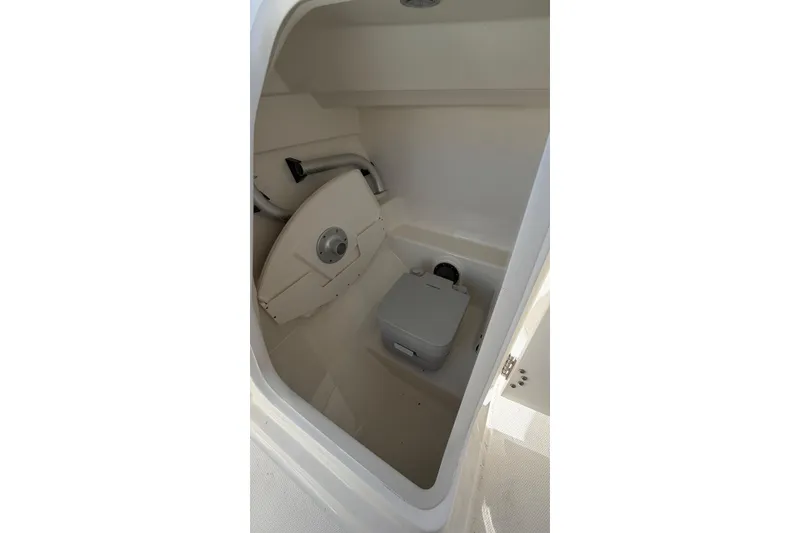 Slide: The Image of 2024 Boston Whaler 210 Vantage boat interior with compact toilet and storage area. - 7