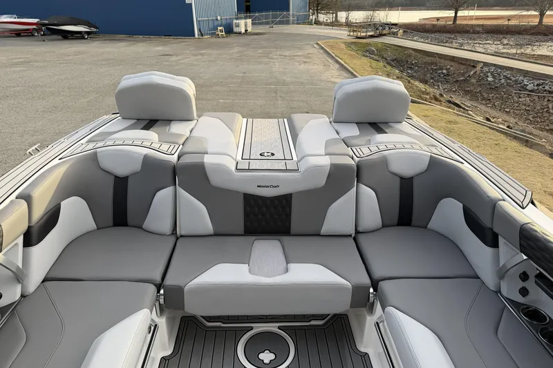 Slide: The Image of 2023 MasterCraft XT24 boat interior with gray and white seating, docked near a lake. - 11