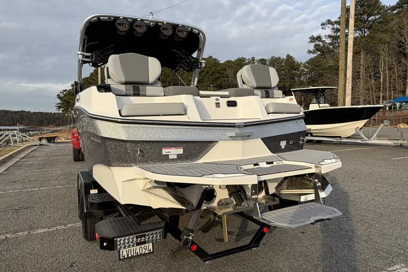 Slide: The Image of 2023 MasterCraft XT24 boat on trailer, rear view, parked outdoors. - 2
