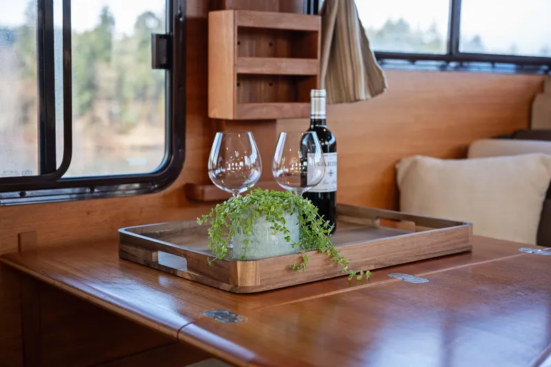 Slide: The Image of Interior of 2014 Ranger Tug R-31 CB with wine, glasses, and plant on wooden table. - 12