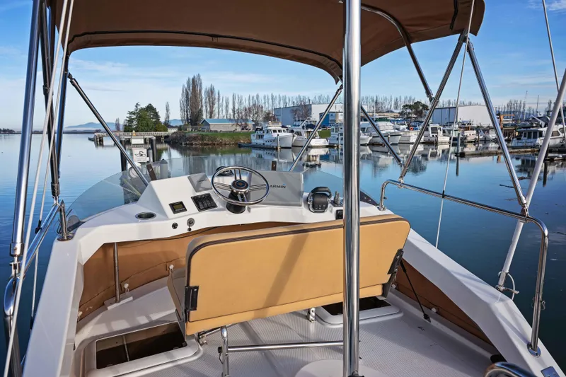 Slide: The Image of 2014 Ranger Tug R-31 CB helm with marina view, featuring tan seating and clear skies. - 15