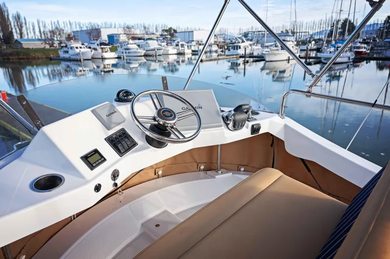 Slide: The Image of 2014 Ranger Tug R-31 CB helm with marina view, featuring Garmin navigation system. - 16