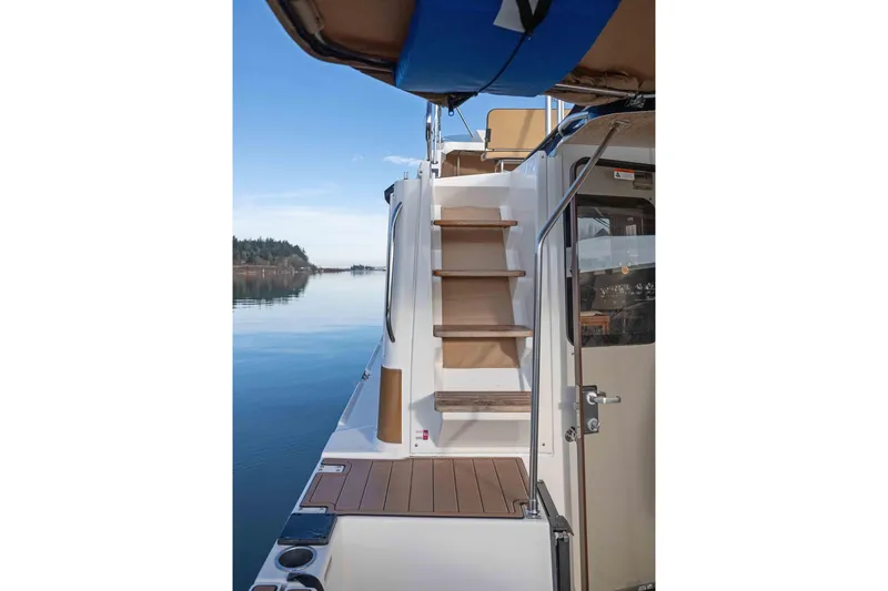 Slide: The Image of 2014 Ranger Tug R-31 CB boat with wooden steps and serene water view. - 20