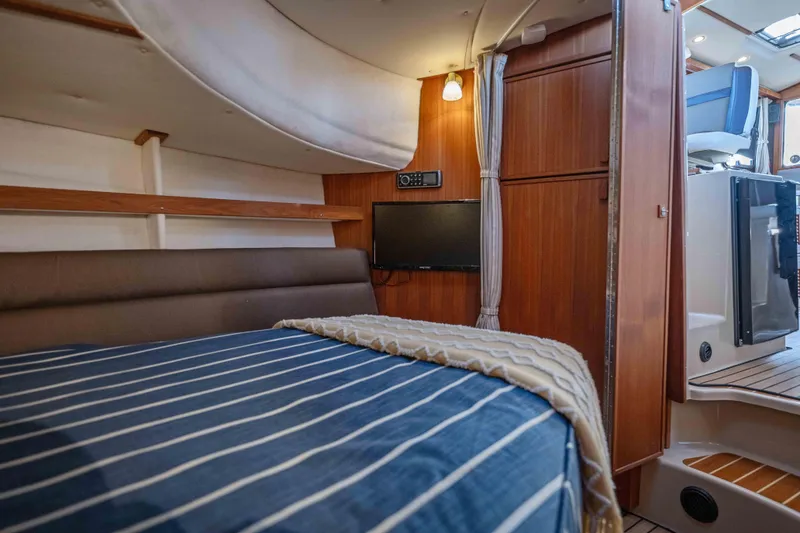 Slide: The Image of Cozy cabin interior of 2014 Ranger Tug R-31 CB with striped bedding and wood paneling. - 27